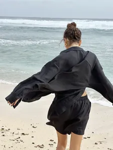 Back view of a black long-sleeved shirt and shorts set worn on a windy beach setting.