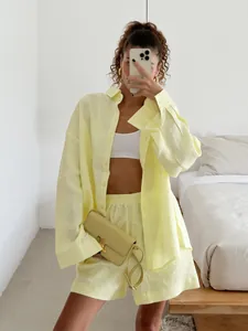 Model wearing a pale yellow minimalist cotton long-sleeve shirt and shorts set indoors.