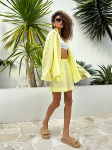 Side view of woman in yellow oversized shirt and shorts set with tropical backdrop