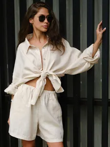Detail view of beige linen two-piece resort set with long sleeve knotted shirt and shorts