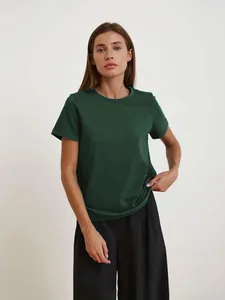 Elegante Frau in einem dunkelgrünen T-Shirt mit Rundhalsausschnitt in einem Studio.
