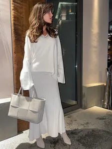 Elegant white knit V-neck sweater and matching ribbed skirt set in outdoor evening setting