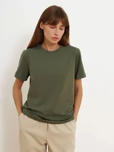 Weibliches Model trägt ein dunkelgrünes Kurzarm-T-Shirt mit Rundhalsausschnitt im Stil