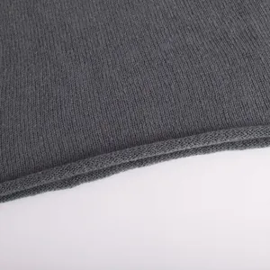 Close-up of the fine texture and rolled hem of the dark gray knitted sweater.