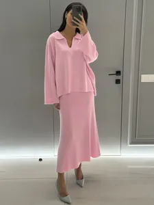 Minimalist pink knit two-piece set featuring V-neck sweater and elegant midi skirt.