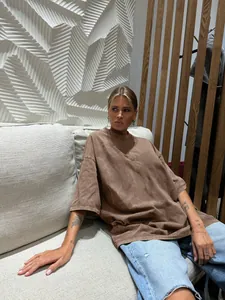 Detail view of oversized brown vintage washed cotton T-shirt worn by a model in a modern interior