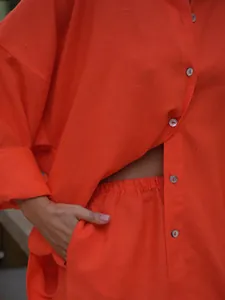 Close-up of orange linen-blend shirt and shorts set showing fabric texture and buttons