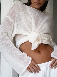 Detail of white sheer hollow knit sweater with flare sleeves and front-knot styling.