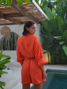 Vibrant orange two-piece resort set with loose shirt and shorts in tropical pool setting