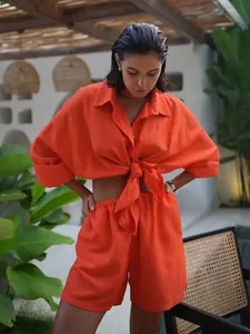 Detailed shot of vibrant orange linen-style resort shirt and shorts set on model