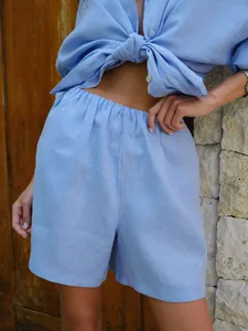 Detail of light blue linen shirt and high-waist shorts set for summer leisure resort style