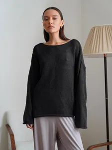 Detailed view of women's black sheer knit sweater with bell sleeves and boat neck