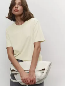 Nahaufnahme einer Frau in einem minimalistischen, hellgelben Kurzarm-T-Shirt mit Rundhals.