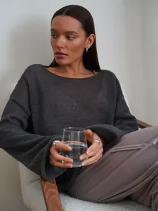 Lifestyle detail of a sheer charcoal knit sweater featuring wide neckline and long bell sleeves