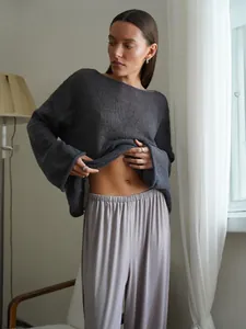 Detail view of a lightweight sheer dark grey knit sweater featuring flared sleeves and neck