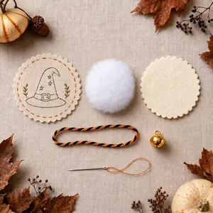Halloween embroidery DIY kit components with fabric, bell, cord, and needle details.