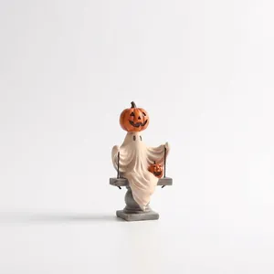 Détail d'une figurine de fantôme sur une balançoire avec une citrouille pour Halloween