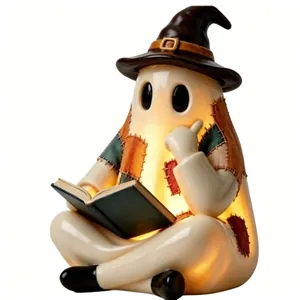 Primer plano de una figura de resina de fantasma de Halloween que lee un libro con luz