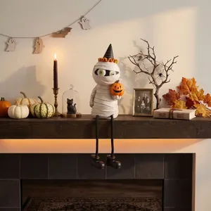 Figurine de momie d'Halloween posée sur une cheminée avec décorations d'automne