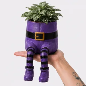 Vue rapprochée d'un pot de fleurs Halloween fantaisiste en résine tenu à la main
