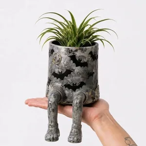 Vue détaillée du pot de fleurs d'Halloween à jambes suspendues tenu dans la main