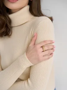 Detailansicht einer Frau im beigen Rollkragenpullover mit einem goldenen Croissant-Ring