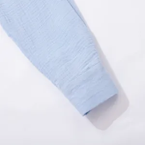 Dettaglio del polsino di una camicia in garza di cotone stropicciata azzurra e trama.