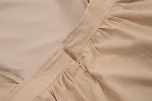 Detailed view of apricot cotton dress featuring a hidden zipper and pleated waist detail