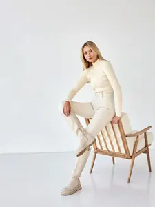 Full view of slim fit cream mock neck ribbed knit sweater worn by female model