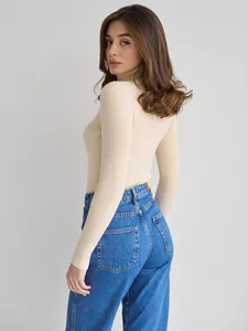 Nahaufnahme eines cremefarbenen Rippstrick-Rollkragenpullovers mit Jeans