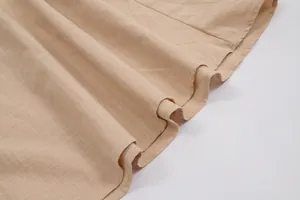 Close-up detail of beige pure cotton dress fabric with natural texture and pleated hem