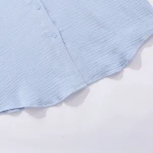 Vista dettagliata del tessuto in cotone stropicciato azzurro e bottoni su camicia estiva