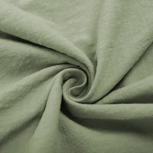 Macro view of sage green cotton fabric showing soft natural texture and linen-like weave