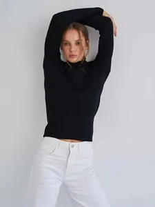 Detail of black mock-neck ribbed sweater on model showing snug fit and soft texture