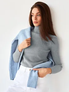 Nahaufnahme eines grauen Rollkragenpullovers kombiniert mit blauer Strickjacke