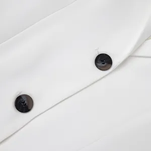Dettaglio dei bottoni tartarugati e del tessuto bianco di un blazer da donna sfiancato