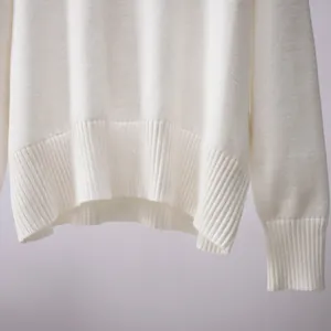Nahaufnahme des Saums und der Rippbündchen eines weißen Strickpullovers für Damen