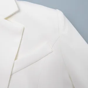 Dettaglio ravvicinato del colletto e delle cuciture di un blazer bianco da donna.