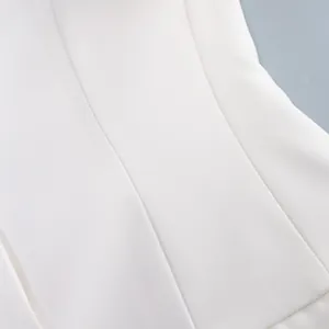 Dettaglio ravvicinato del tessuto bianco di un blazer sfiancato con cuciture sartoriali.