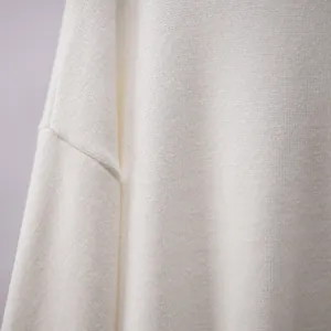 Nahaufnahme eines weichen weißen Strickpulvers mit Details zur Schulternaht und Textur.