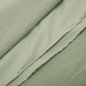 Close-up detail of sage green cotton dress fabric texture and fine stitching seam