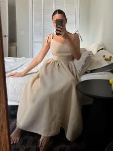 Mirror selfie of woman in beige cotton V-neck maxi dress with tie-straps