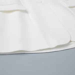 Dettaglio ravvicinato di un blazer bianco sciancrato da donna con orlo e qualità tessuto