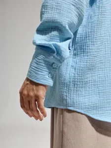 Dettaglio del polsino a bottoni di una camicia in cotone crepe traspirante azzurro