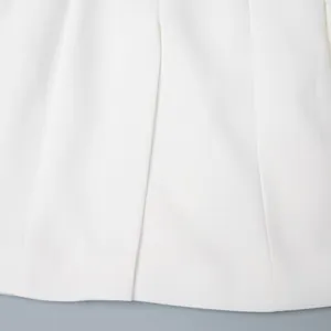 Dettaglio del tessuto del blazer bianco che mostra la trama fine e le cuciture