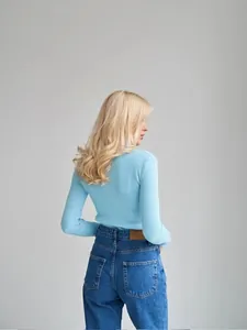 Back view of a woman wearing a slim-fit light blue ribbed turtleneck sweater.