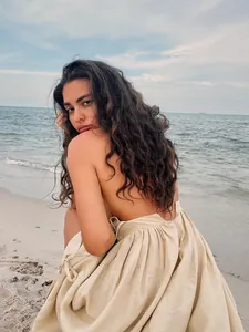 Detailed rear view of an elegant beige backless cotton dress worn on a beach setting.