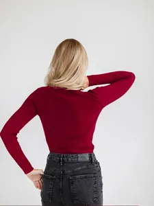 Back view of a slim-fit burgundy ribbed knit turtleneck sweater worn by a model