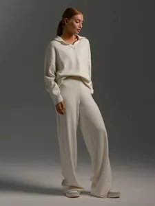 Model wearing a cozy cream knitted polo sweater and wide-leg pants set in a studio setting.