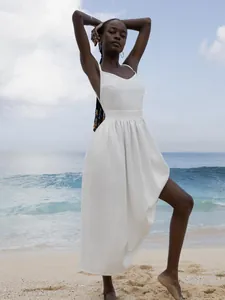 Elegant white V-neck cotton strap dress featuring an open back on a sunny beach